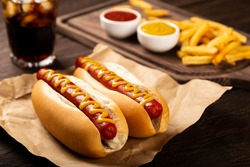 Hot dogs with ketchup, yellow mustard, french fries and soda. Image with selective focus.