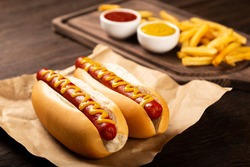 Hot dogs with ketchup, yellow mustard and fries. Image with selective focus