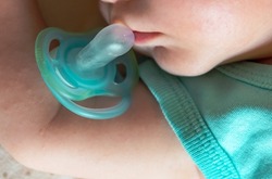 Blue pacifier falling from the mouth of a sleeping newborn baby boy.Close-up of the face of 2-month old baby.
