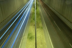 Light trails on the underpass road at night. Traffic or highway background photo. Two lanes road and light trails of cars.