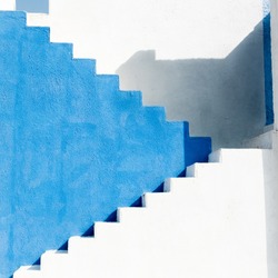 Colorfully painted staircase with contrast blues and whites. building shadows make this image an abstract background. 