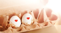 a couple of eggs marked
with hearts in a cardboard box