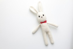 Handmade children's toy - soft crocheted white Bunny. Large knitted stuffed rabbit with eyes made of buttons on white background - the concept of happy childhood