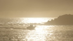 Small fishing boat travelling past the North Haven Break-wall on a golden sunrise morning.