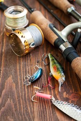 Fishing tackle - fishing spinning, fishing line, hooks and lures on wooden background