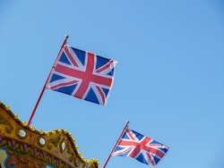 Two Union Jacks fluttering in breeze against blue sky