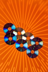Variety of Arranged CD Disks or DVD Disks on Orange Background With Different Circular Rays Patterns or Masks. Vertical Image Composition