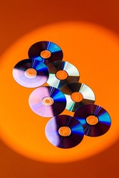 Variety of Arranged CD Disks or DVD Disks on Orange Background With Different Circular Patterns or Masks.Vertical Image Composition