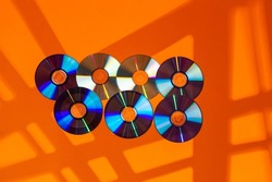 Variety of Arranged CD Disks or DVD Disks on Orange Background With Different Rectangular Rays Patterns or Masks.Horizontal Shot