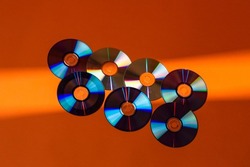 Large Variety of Arranged CD Disks or DVD Disks on Orange Background With Different Linear Patterns or Masks.Horizontal Image
