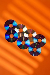 Large Variety of Arranged CD Disks or DVD Disks on Orange Background With Different Patterns or Masks.Vertical Image