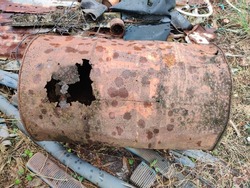 The rusted steel tank rotted into holes. Cannot be used to be placed on the ground with piles of useless items. being placed outdoors There are traces of rain falling on the surface of the old tank.