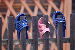Beach sneaker on the fence.Flip flops on the fence. Shoes hanging on a wooden fence. People dry beach shoes. Old boots that fall into the ocean. Slippers are dried in the fresh air.