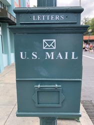 The close up view of a vintage looking mailbox. There is a slot labeled LETTERS, the pictogram of an envelope, and the words U.S. MAIL written across it.