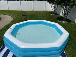 The top down, close up view of an octagon shaped, inflatable, swimming pool in a suburban backyard.
