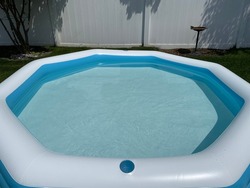 The top down, close up view of an octagon shaped, inflatable, swimming pool in a suburban backyard.
