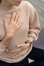 Close-up of a woman's hands on her chest while doing breathing exercises. Caucasian woman sitting in a lotus position, practicing pranayama