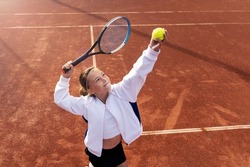 Pretty sports girl with racquet at the tennis court. Tennis player serving. Healthy lifestyle