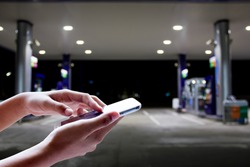Girl use mobile phone ,blur image of gas station as background.