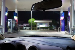 In the car, blur image of gas station as background.
