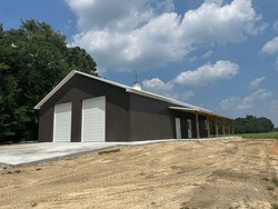 Post frame building pole barn with two roll-up doors, concrete floor, metal siding and roofing, lean-to and cupola