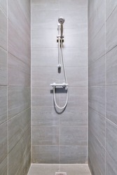 A narrow shower room with dark tiles and a convenient faucet