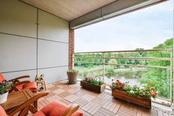The interior of a stunning balcony with red armchairs and a beautiful view of the canal