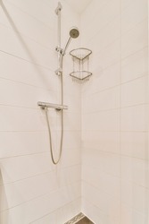 Shower faucets attached to tiled wall near glass partition and ornamental curtail in washroom at home