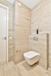 Interior of narrow restroom with wall hung toilet with white walls and checkered floor