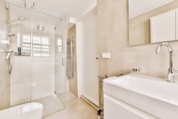 Sinks with mirrors and clean bathtub located near shower box with glass door in modern bathroom with white tiled walls