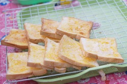 Grilled bread with butter and sugar on gridiron and green tray with selective focus and blurred background.Thailand street food.