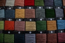 an even row of bobbins with floss threads. goods for hobbies, creativity and embroidery, cross-stitching and quilting. Spool of thread different collors for dark background.