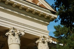 Capital at the top of the column. A beautiful architectural element. The top of the column. An old building next to a pine tree. House of Officers of the Russian Army. Blagoveshchensk, Russia.