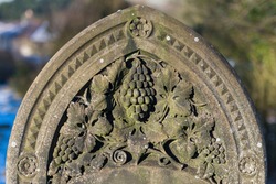 Grave stone with ornate grape and grapevine with leaves carved into the stone.
