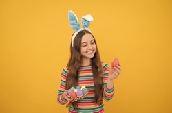 happy easter child girl in rabbit bunny ears showing painted eggs for holiday, happy easter