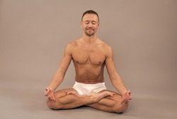 Yogi man meditate sitting in lotus yoga position grey background, meditation