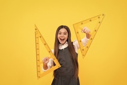 happy child hold math triangle ruler in school on yellow background, education