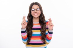 Teenager child holding fingers crossed for good luck. Portrait of cheerful girl prays and hopes dreams come true, crosses fingers for good luck, closes eyes, isolated on white studio background.