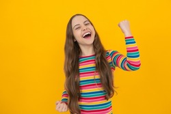Studio portrait of teenager child doing winner gesture. Kid rejoicing, yes victory champion gesture, fist pump. Excited face, cheerful emotions of teenager girl.