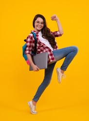 Back to school. Teenager schoolgirl hold notebook laptop. School children on isolated yellow studio background. Run and jump, jumping kid.