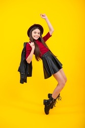 Fashion trendy kids look, child model in vogue fashionable style outfit. Happy teenager portrait. Smiling girl. Full size walk on isolated studio wear hat, casual wear, fashion skirt and shoes.