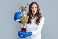 Woman in boxing gloves hold champion winner cup, trophy. Excited win woman in boxing gloves. Winning success power woman. Girl smiling and screaming for success. Celebration concept.