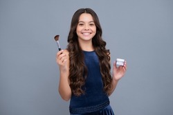 Beautiful portrait of teen girl child artist apply powder with make up brush. Makeup products. Beauty, and cosmetics for teenagers. Happy girl face, positive and smiling emotions.