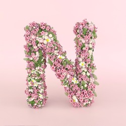 Creative letter N concept made of fresh Spring wedding flowers. Flower font concept on pastel pink background.