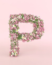 Creative letter P concept made of fresh Spring wedding flowers. Flower font concept on pastel pink background.
