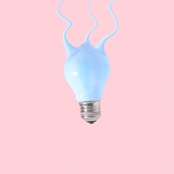 Creative concept of a light bulb from which blue paint flows on pastel pink background.