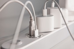 Many chargers plugged into maltiple electrical outlet on white background. Concept of electricity consumption.