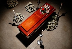 closed wooden coffin with candles and flowers in a dark and gloomy environment