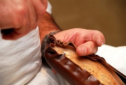Cobbler's hands, man crafting a shoe using cobbler's tools. Placing the skin in a last.