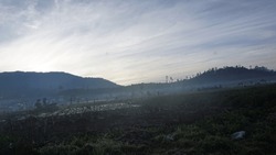The Dieng landscape bathes in the early morning's enchanting mist, weaving an ethereal tapestry of wonder and intrigue.